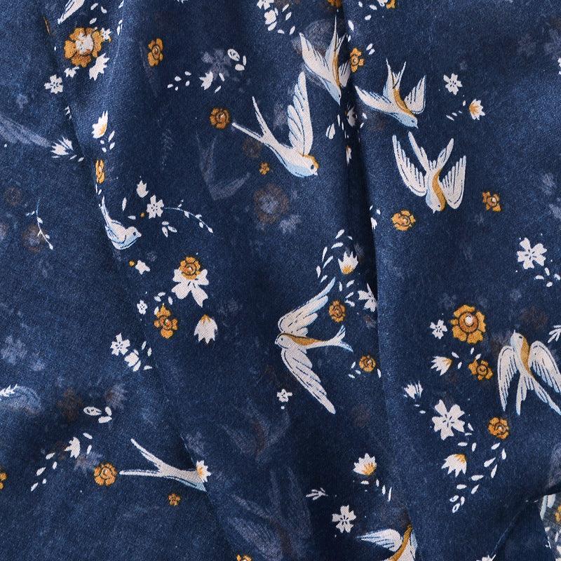 Blue fabric with white and orange bird and floral pattern, soft texture background