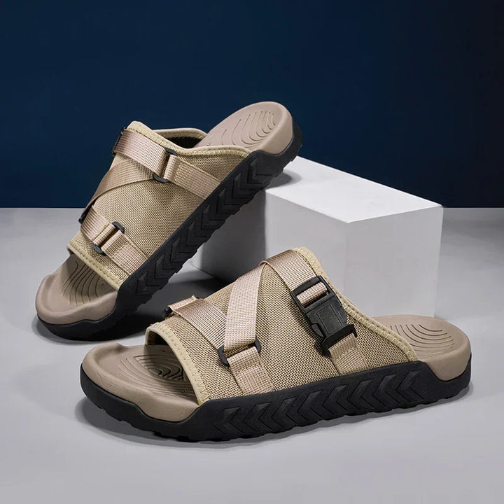 Beige casual slide sandals with adjustable straps and black rugged soles on gray surface