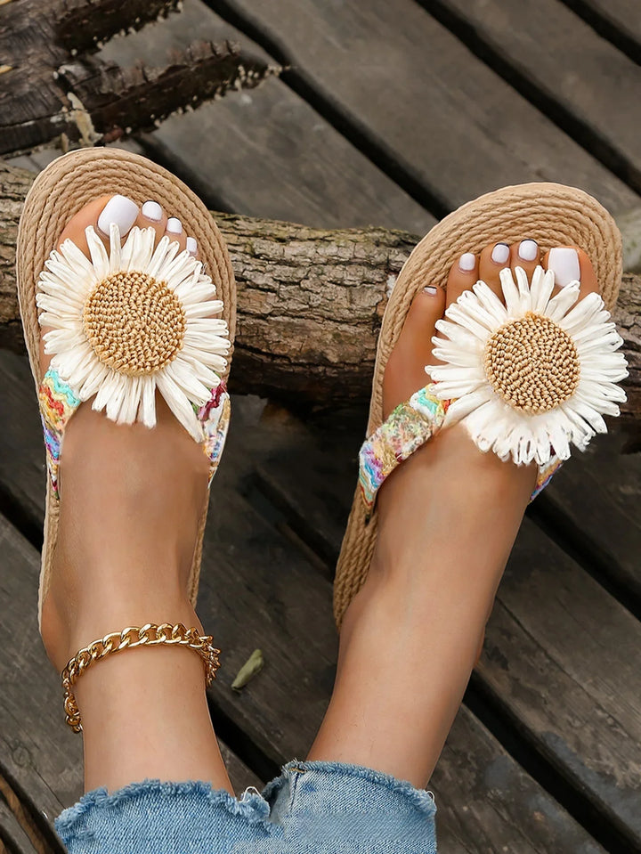 Woman wearing floral daisy sandals with white painted toenails on wooden deck