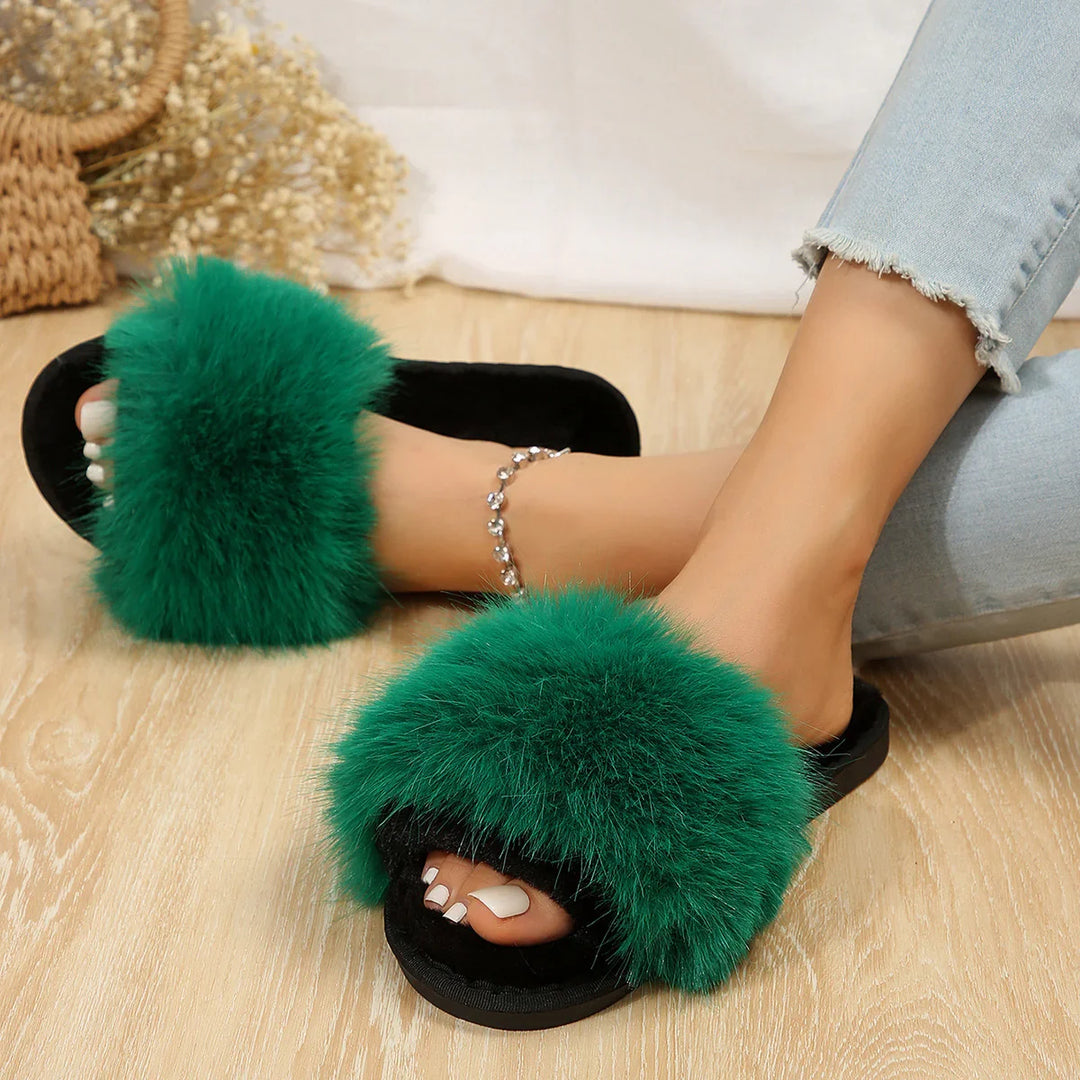 Woman wearing green fluffy slides with black soles and light blue jeans on wood floor