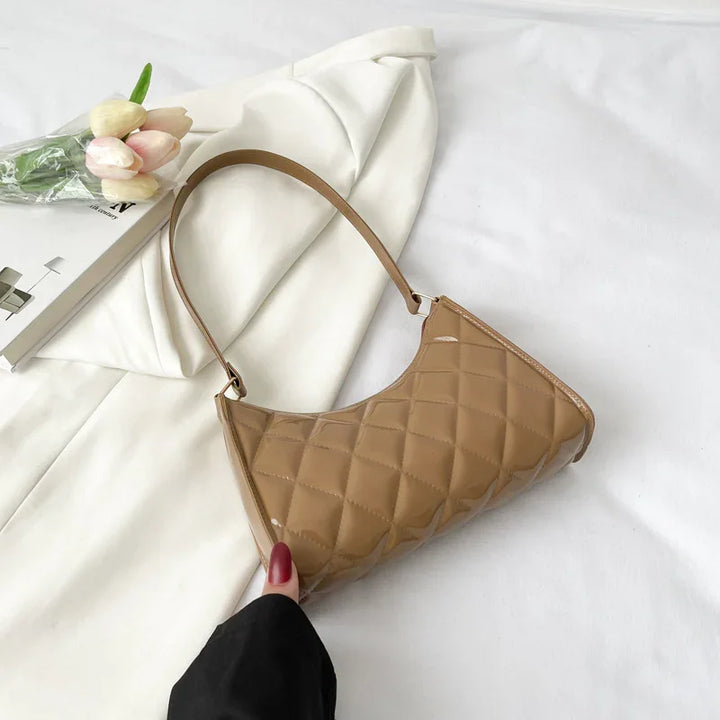 Glossy beige quilted handbag with a single strap on white fabric and a white blazer with tulips