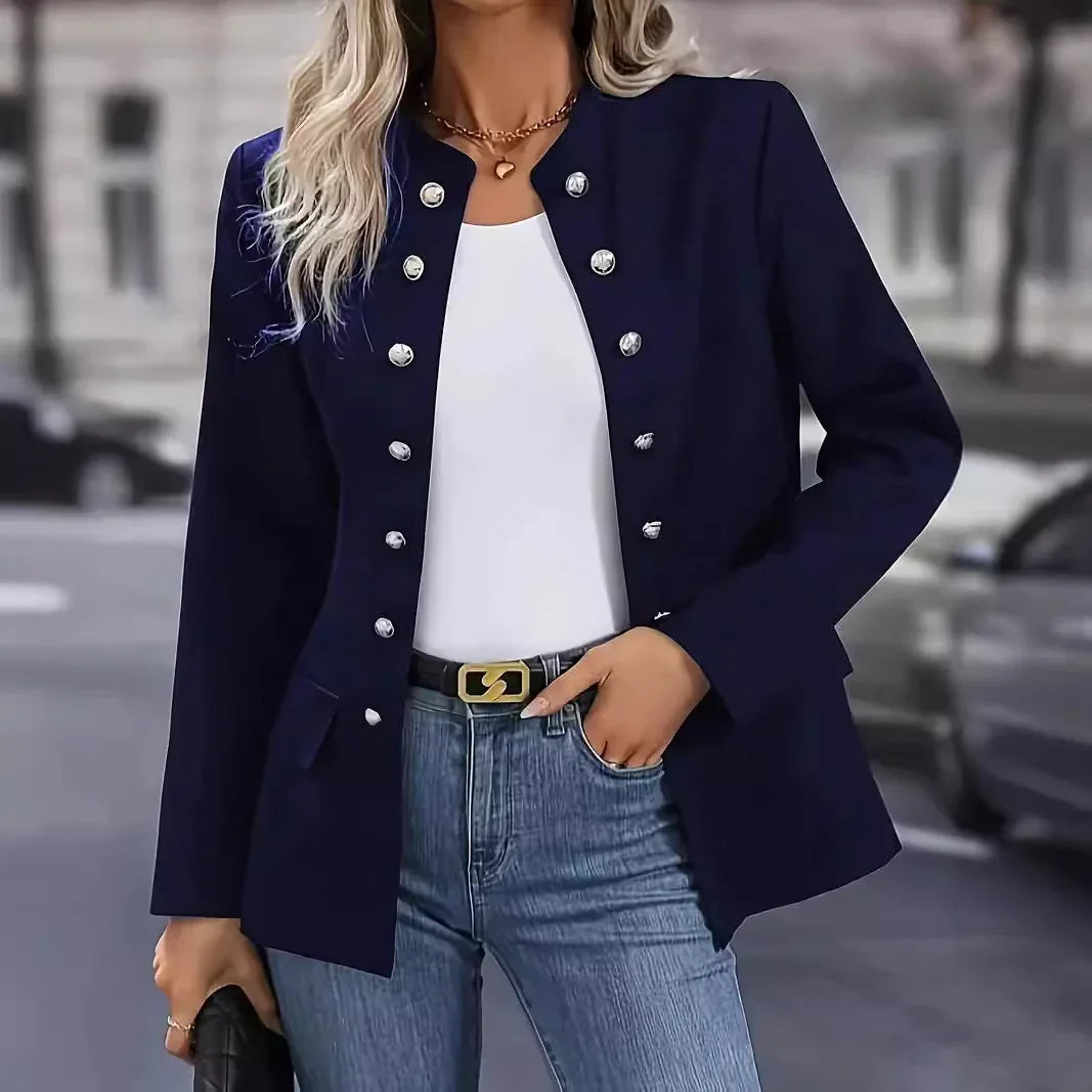 Woman wearing navy blue buttoned blazer with white top and blue jeans, holding black purse