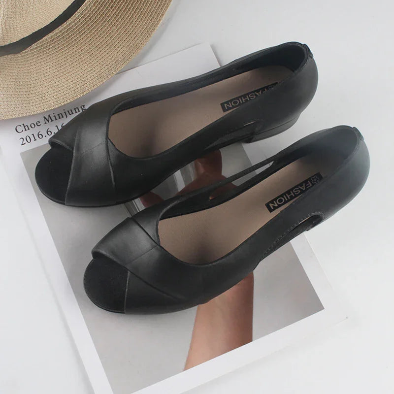 Black peep-toe flats on magazine page with straw hat edge visible