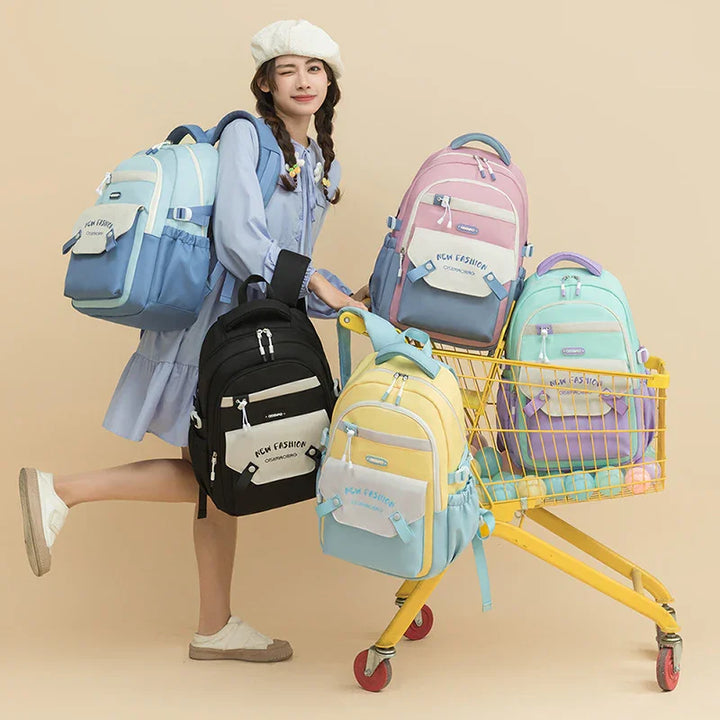 Young woman in blue dress and beret posing with colorful fashion backpacks and yellow shopping cart
