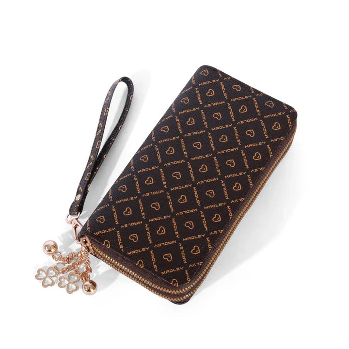 Black zip-around wristlet wallet with gold MADLEY logo pattern and heart charms on zipper pull