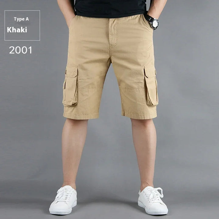 Man wearing khaki cargo shorts with flap pockets and white sneakers against gray background