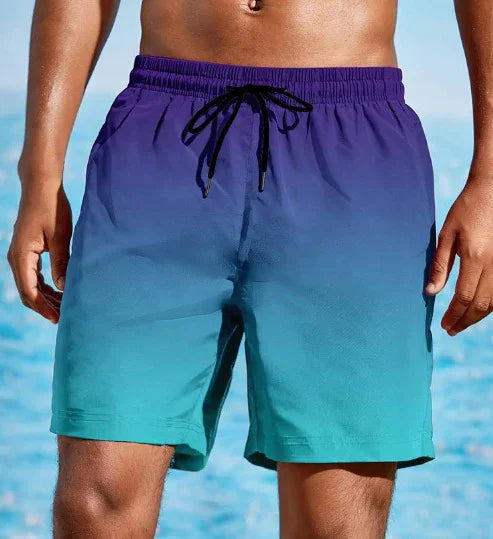 Men's swim trunks with purple to turquoise gradient and black drawstring at the beach
