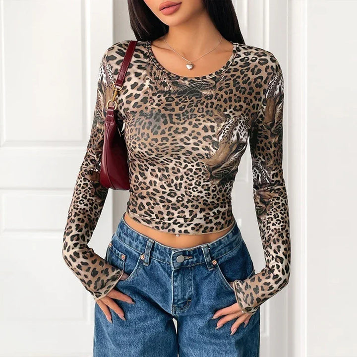 Woman wearing a leopard print long-sleeve crop top paired with high-waisted blue jeans and a maroon shoulder bag