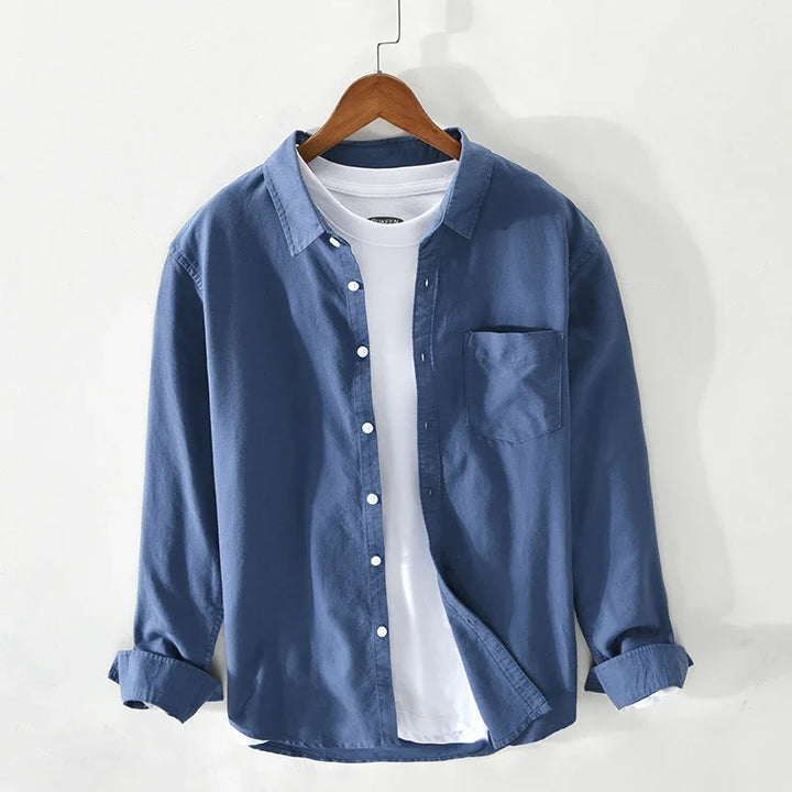 blue button-up shirt layered over white crew neck t-shirt on wooden hanger against white background