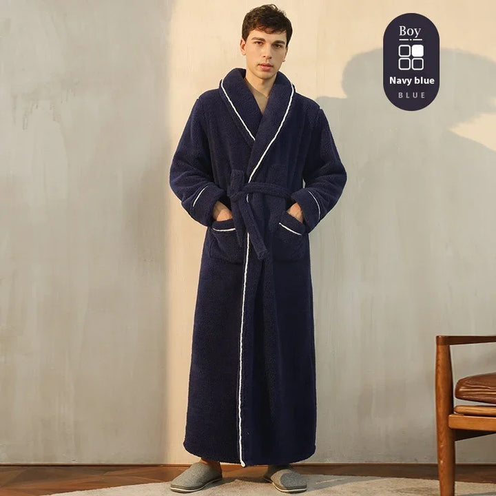 Young man wearing long navy blue plush robe with white trim standing indoors next to wooden chair
