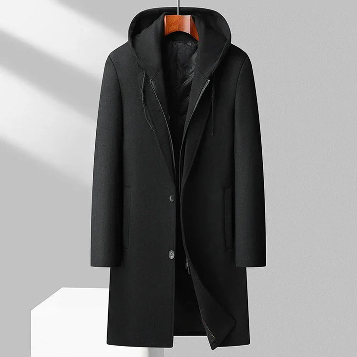 Black men's long wool coat with hood hanging on wooden hanger against gray background