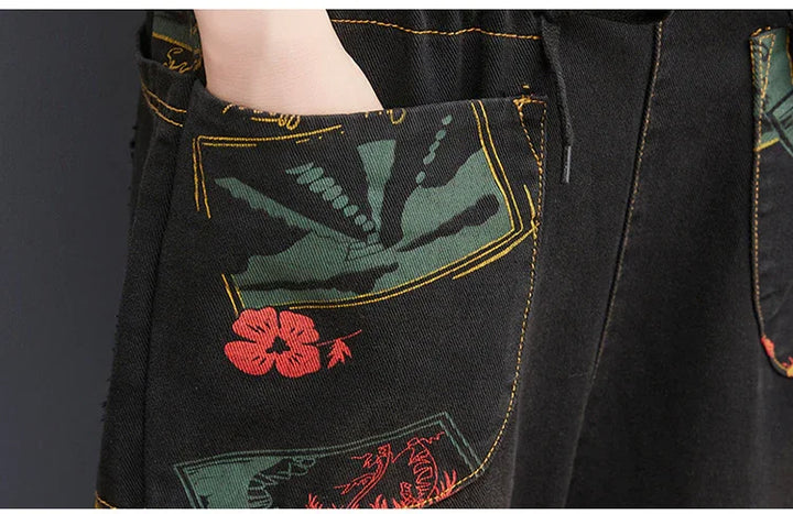 Close-up of black denim pants with green and red floral and abstract stitched pocket designs