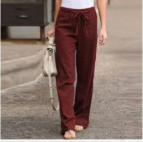 Woman wearing high-waisted, drawstring maroon pants with a white top, walking on a pavement