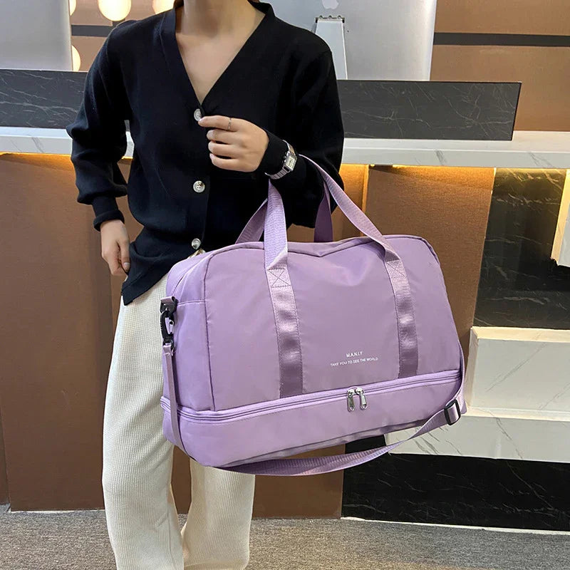 Person holding large purple travel duffel bag with shoulder strap indoors