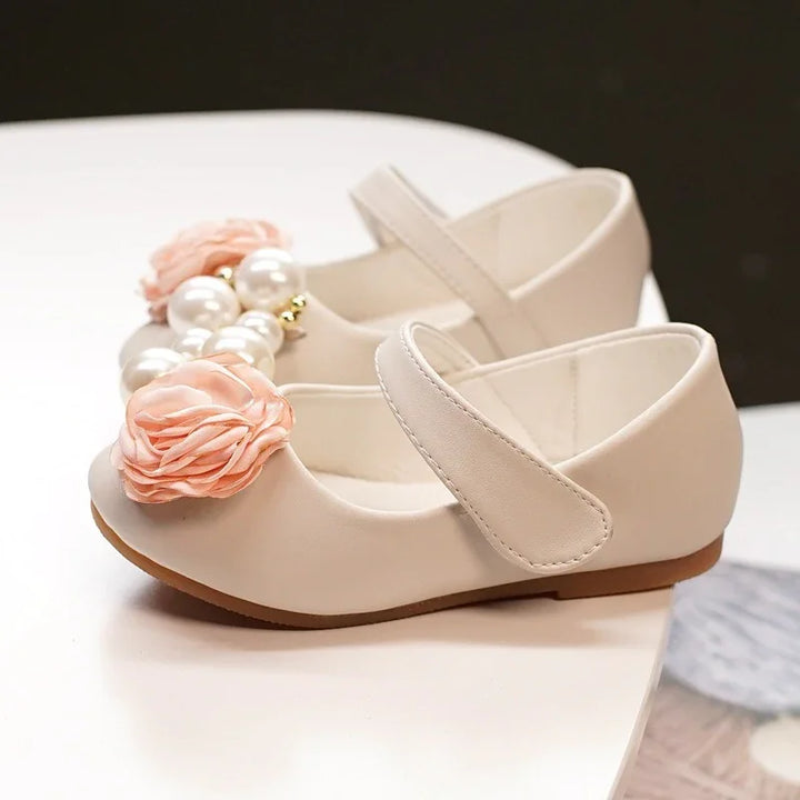 Cream-colored toddler Mary Jane shoes with strap, decorated with peach fabric flowers and large pearl beads