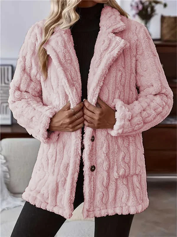 Woman wearing a soft pink faux fur textured coat with button closure over black top indoors