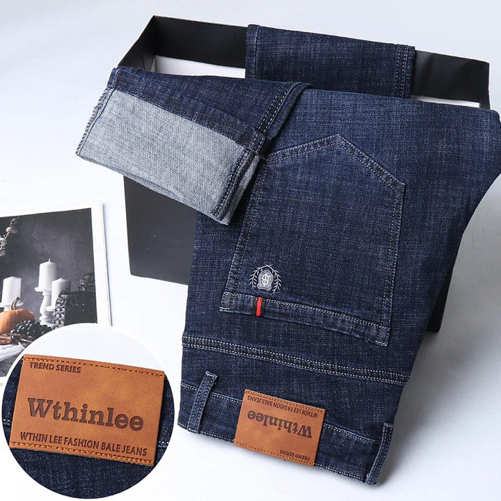 Folded dark blue Wthinlee denim jeans with visible leather brand patch and back pocket detail