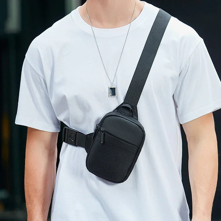 Man wearing white t-shirt with black crossbody sling bag featuring zipper pocket and adjustable strap