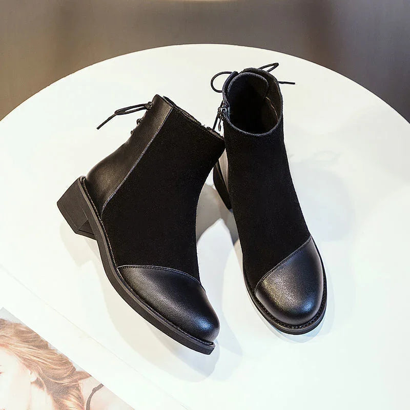 Pair of black ankle boots with leather toe and heel on white round table