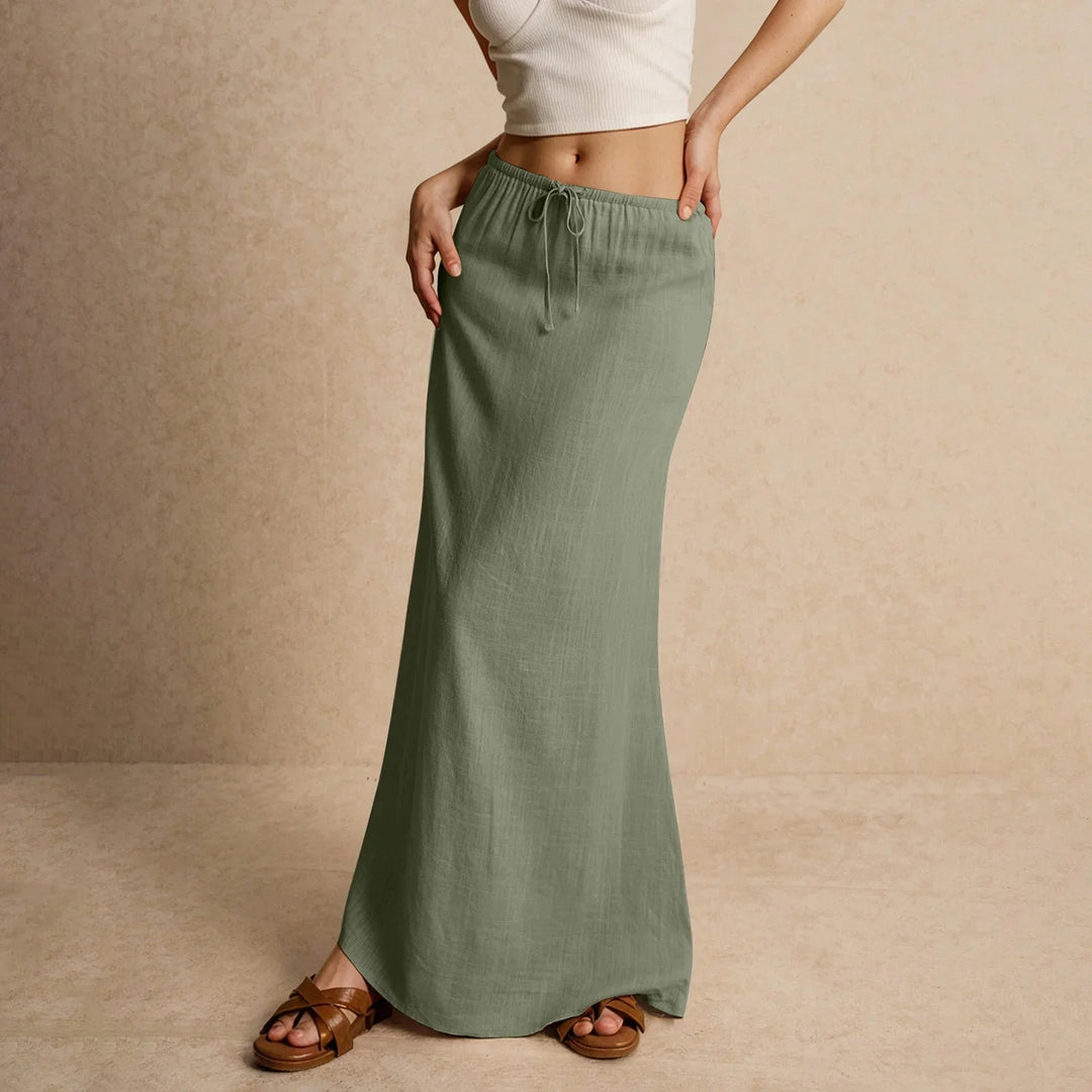 Woman wearing olive green maxi skirt with drawstring waist and white crop top, brown sandals