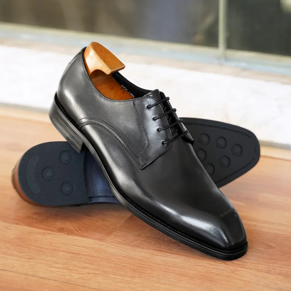 Black leather formal Oxford shoes with laces on wooden surface and shoe tree