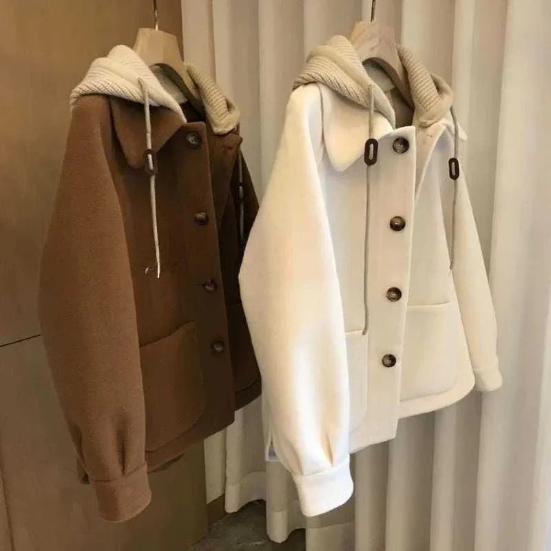 Brown and white button-up fleece jackets with large pockets and hooded collars hanging on wooden hangers