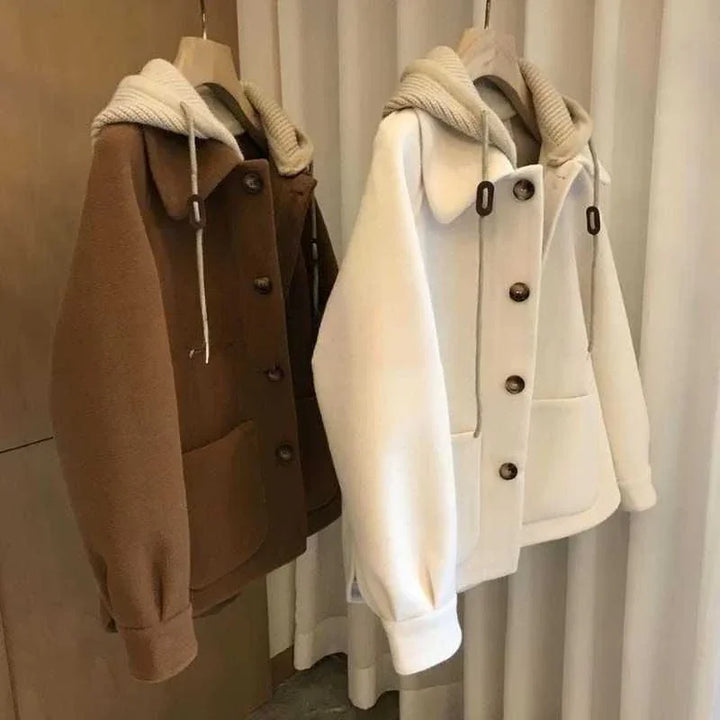 Brown and white button-up fleece jackets with large pockets and hooded collars hanging on wooden hangers