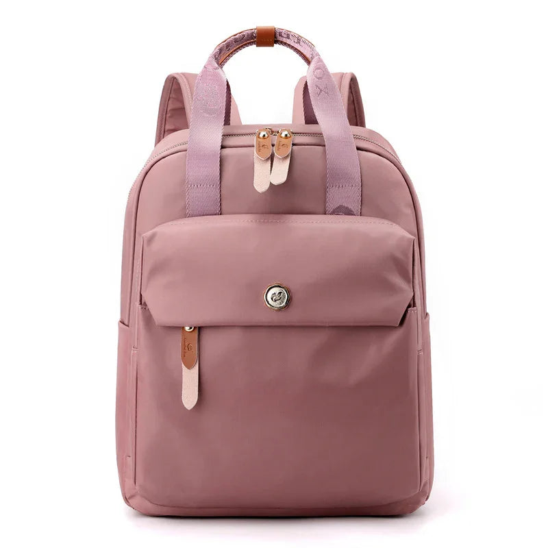 Stylish dusty pink backpack with front flap pocket, leather zipper pulls, and fabric carrying handles