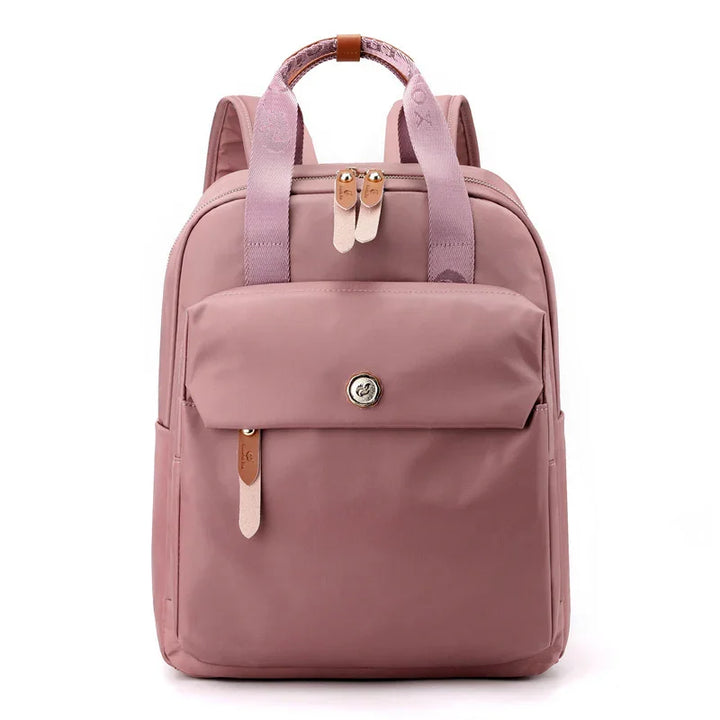Stylish dusty pink backpack with front flap pocket, leather zipper pulls, and fabric carrying handles