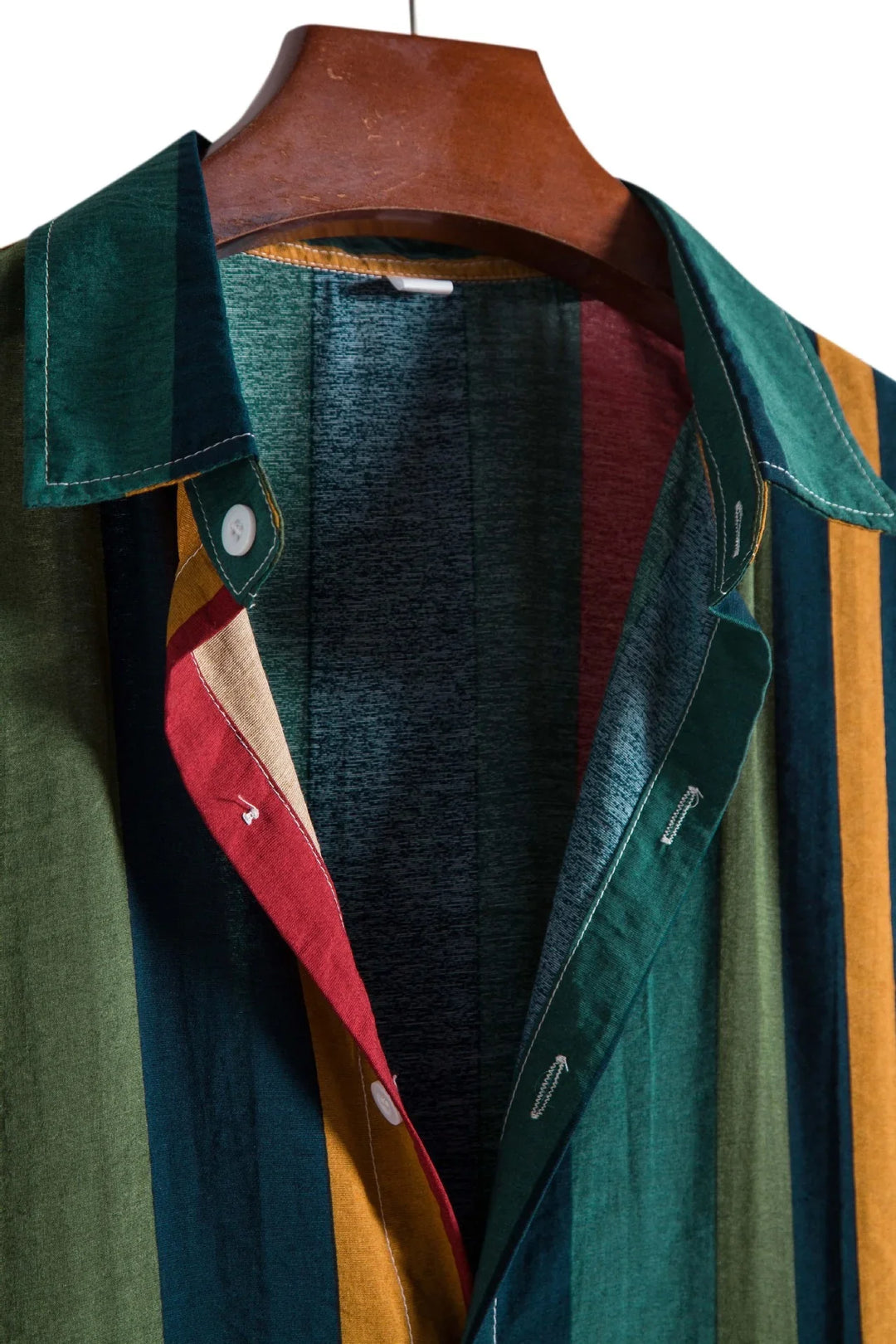 Close-up of a multicolor striped button-up shirt on a wooden hanger with green, red, and yellow stripes