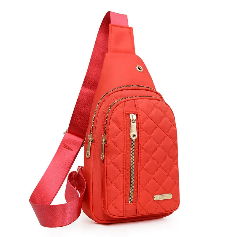 Red quilted sling backpack with multiple zippered compartments and adjustable strap