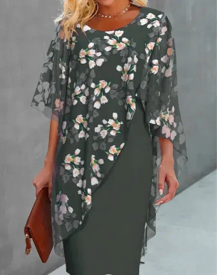Woman wearing dark green floral chiffon poncho dress holding brown clutch purse