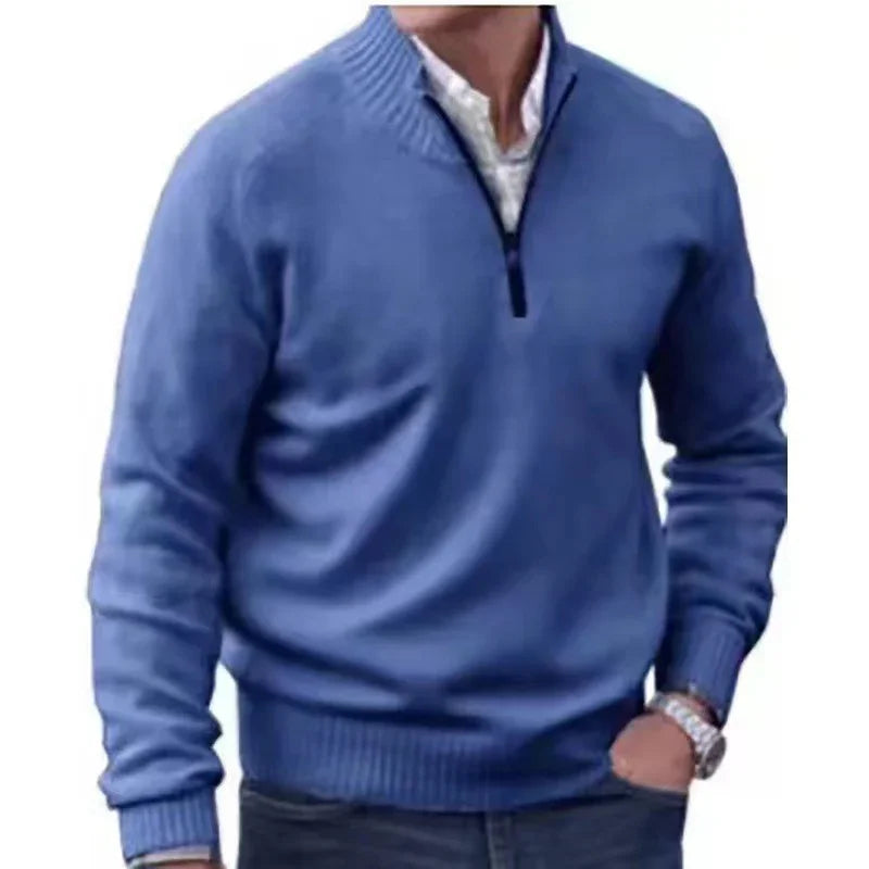 Man wearing a blue quarter-zip sweater over a white shirt with jeans and a wristwatch