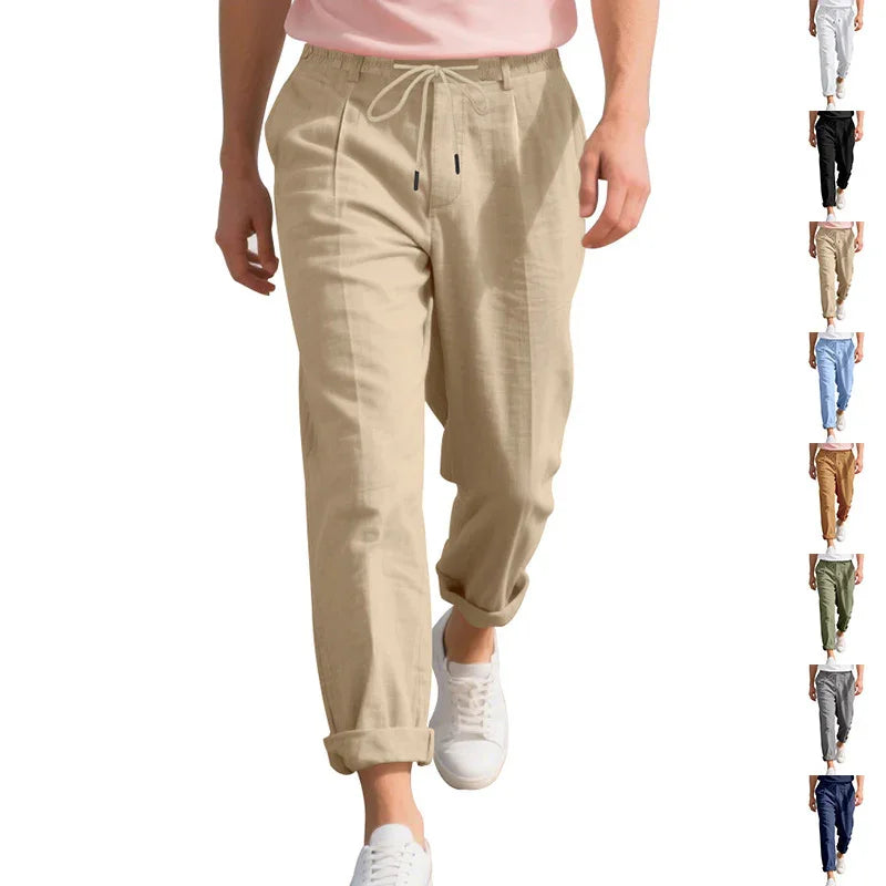 Men's beige linen drawstring pants rolled up at ankles paired with white sneakers and pink shirt