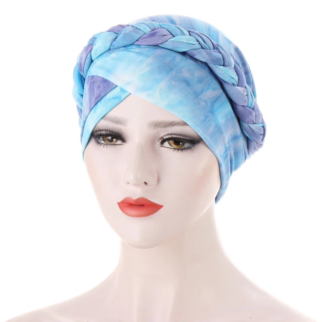woman mannequin head wearing blue and purple braided turban headwrap against white background