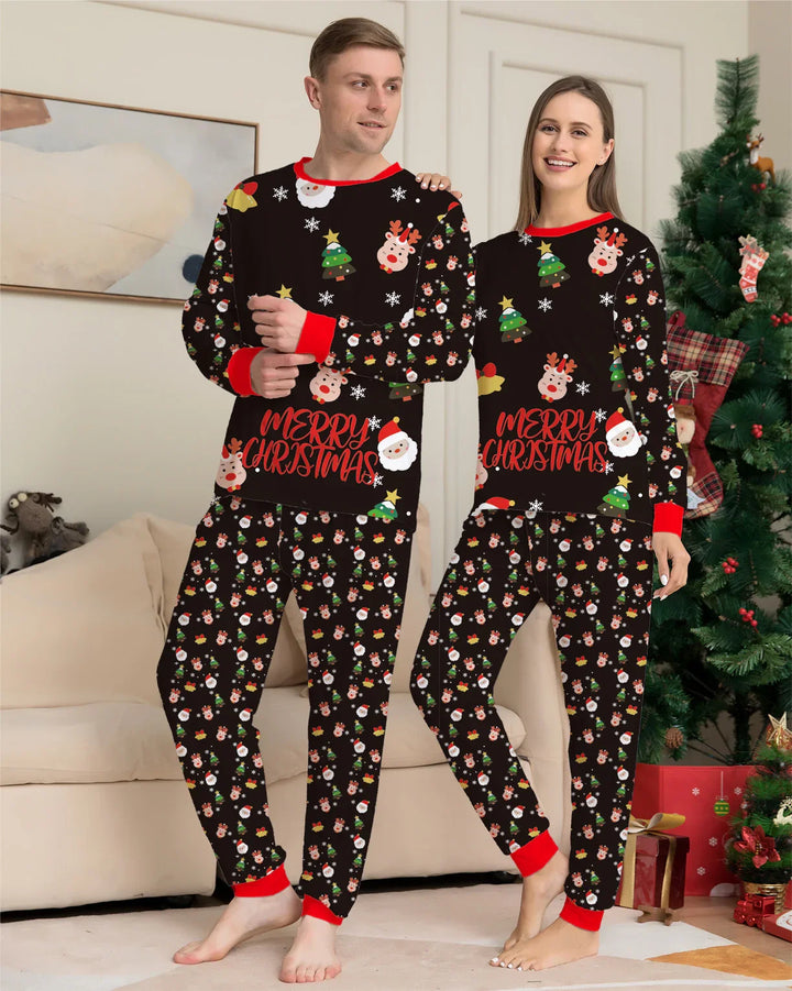 Couple in matching black Christmas pajamas with Santa, reindeer, tree prints and red cuffs standing in festive living room