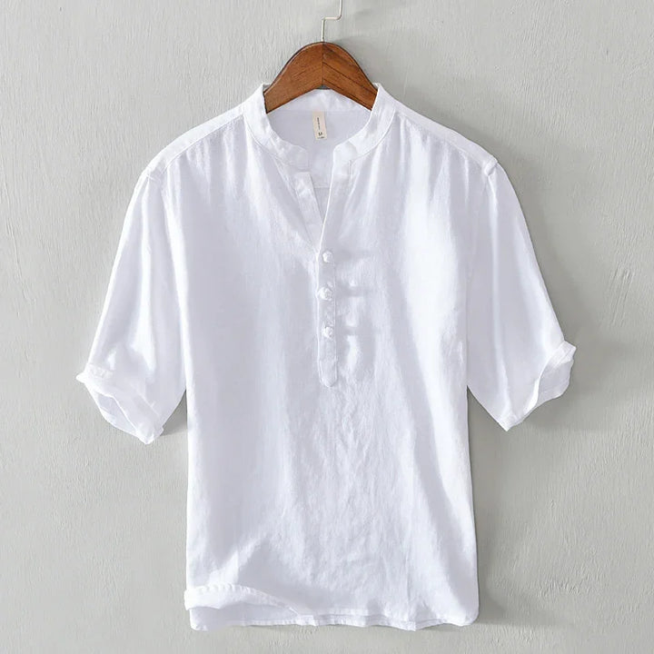 White short sleeve mandarin collar shirt with button placket on wooden hanger against gray wall