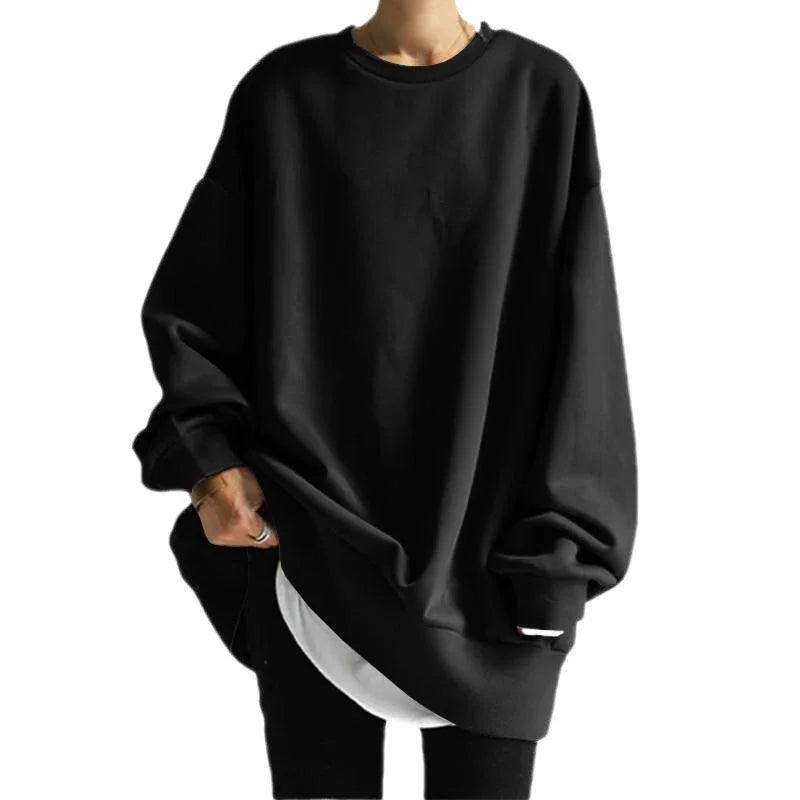 person wearing oversized black sweatshirt layered over white shirt with black pants on white background