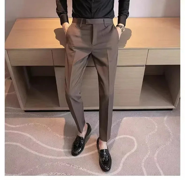 Man wearing stylish brown slim-fit dress pants and black tassel loafers standing indoors