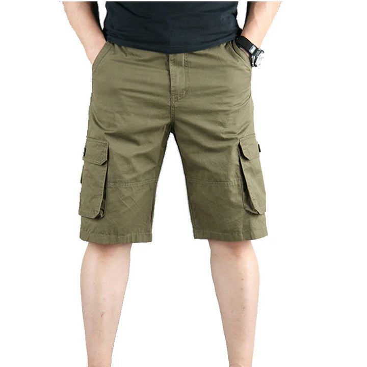 Man wearing olive green cargo shorts with side pockets against white background