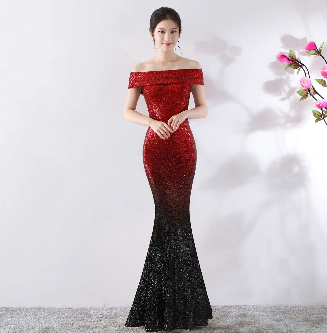 Woman in elegant off-shoulder red to black ombre sequin gown standing on gray carpet beside pink flower branch