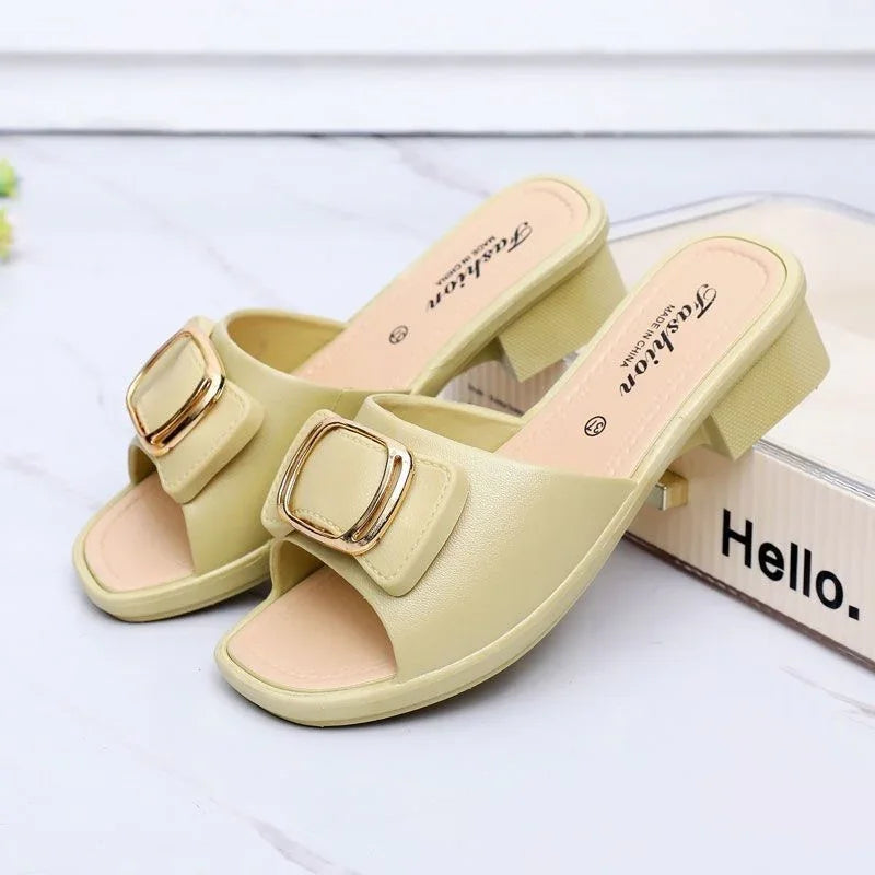 Beige open-toe block heel sandals with gold buckle detail on white marble surface
