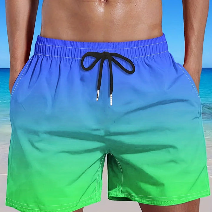 Man wearing blue to green ombre swim trunks with black drawstring at beach background