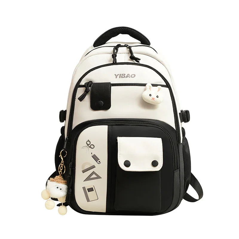 Black and white YIBAO backpack with front pockets, school supplies icons, and cute bunny and plush keychains