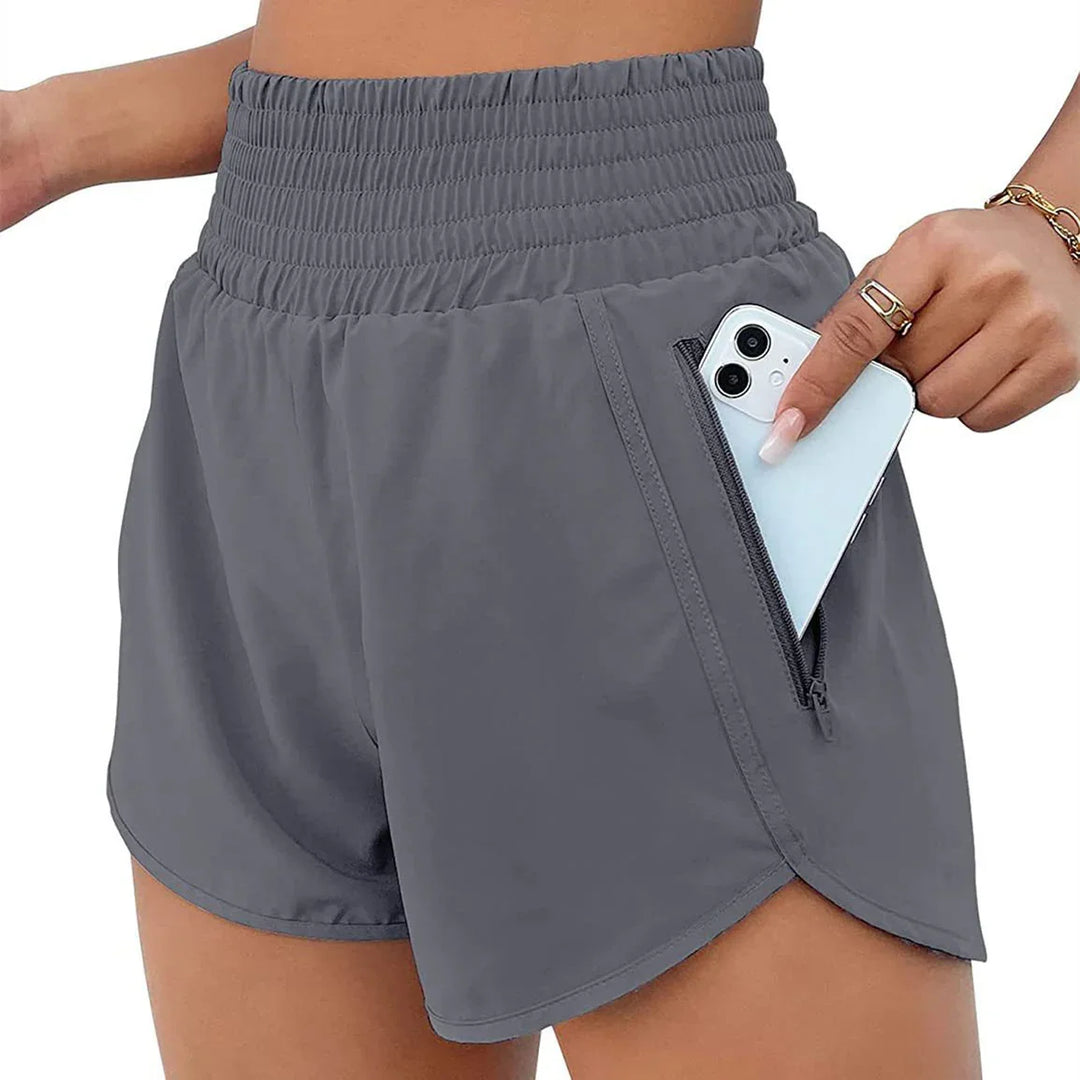 Close-up of gray high-waisted athletic shorts with zippered pocket holding a smartphone