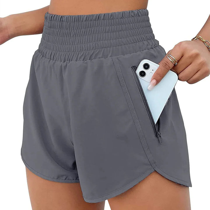 Close-up of gray high-waisted athletic shorts with zippered pocket holding a smartphone