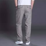 Man wearing light gray casual pants and white sneakers against gray backdrop