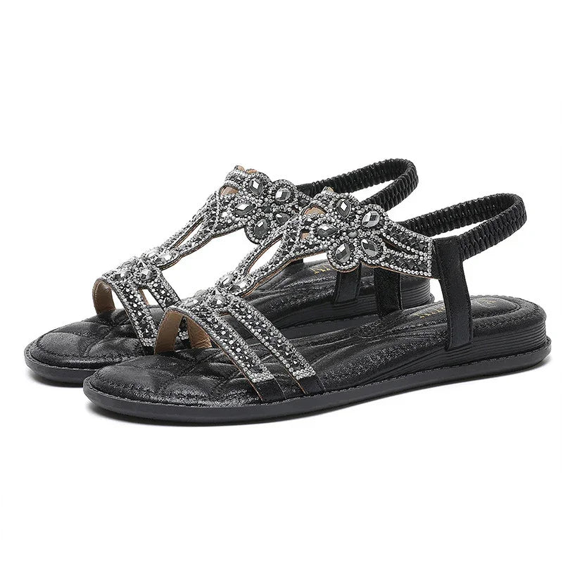 Black flat sandals with elastic back strap and decorative rhinestone floral design