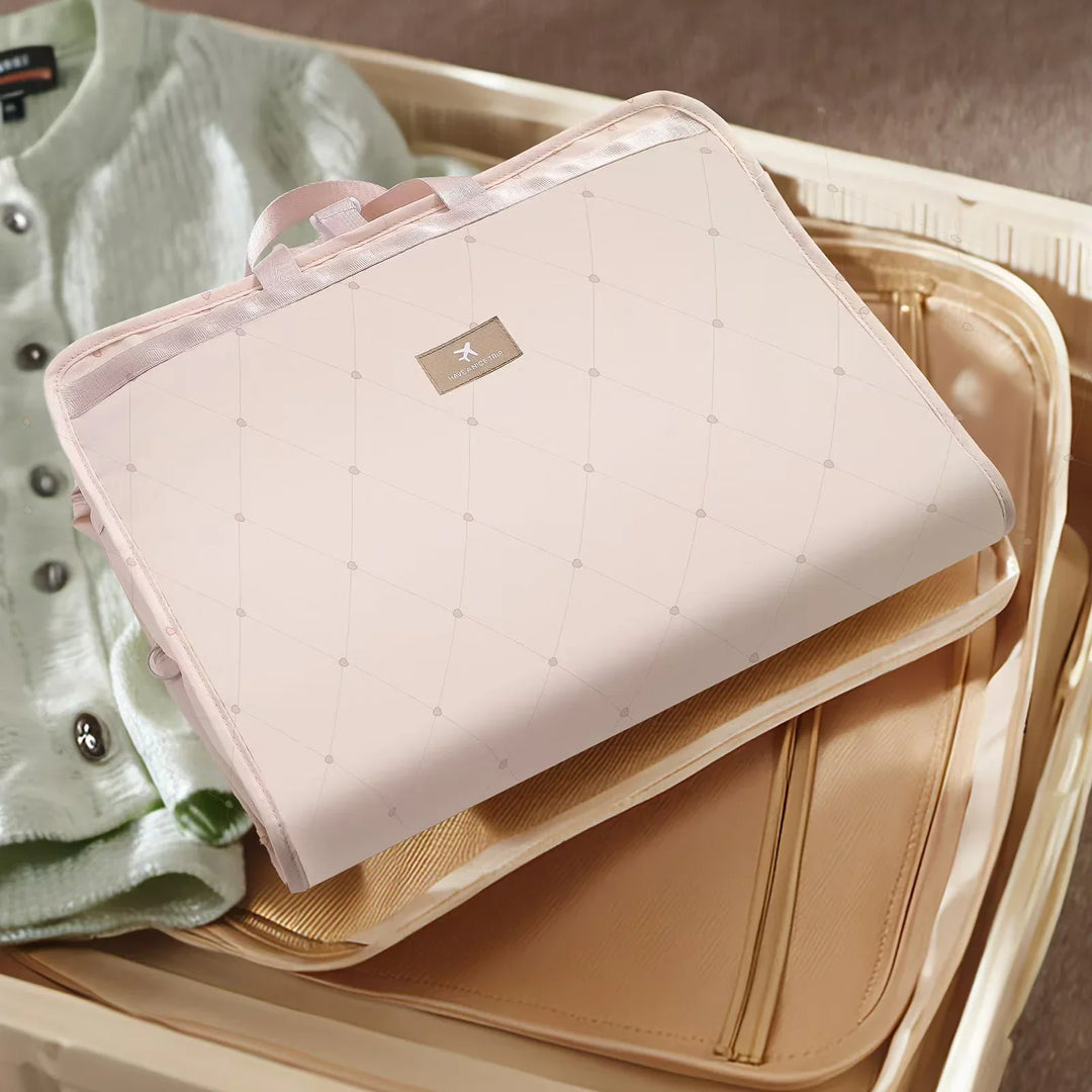 Light pink quilted travel organizer with handle and airline logo, packed in beige suitcase with folded sweater