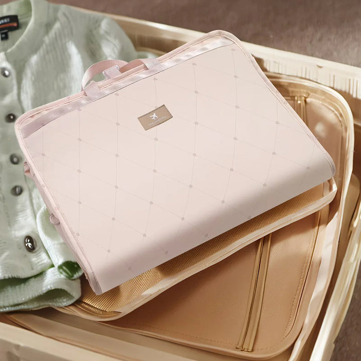 Light pink quilted travel organizer with handle and airline logo, packed in beige suitcase with folded sweater